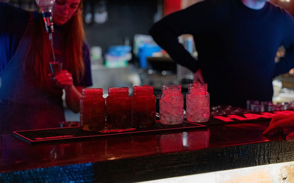 Bartenders building a round of drinks along the bar under red light